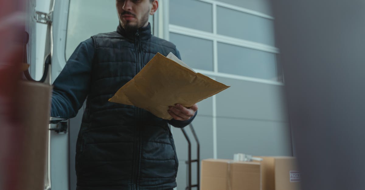 Entregador organizando pacotes ao lado de moto de entregas preparando-se para o trabalho